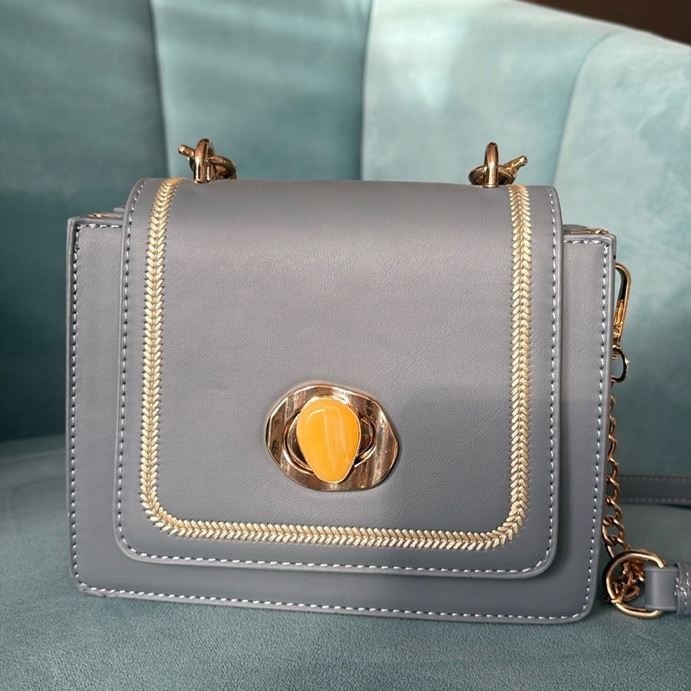 Cute blue small purse with handle and cross body strap. Gold detail